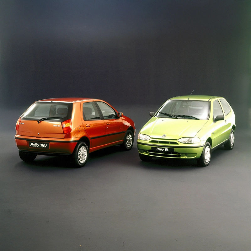 Dois modelos Fiat Palio lado a lado, nas cores laranja e verde, apresentados sobre fundo neutro. Dois modelos Fiat Palio lado a lado, nas cores laranja e verde, apresentados sobre fundo neutro.