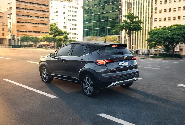Fiat Pulse cinza com teto preto, com logotipo Pulse visível na tampa traseira, rodando em via urbana arborizada, com prédios ao fundo e iluminação natural diurna.