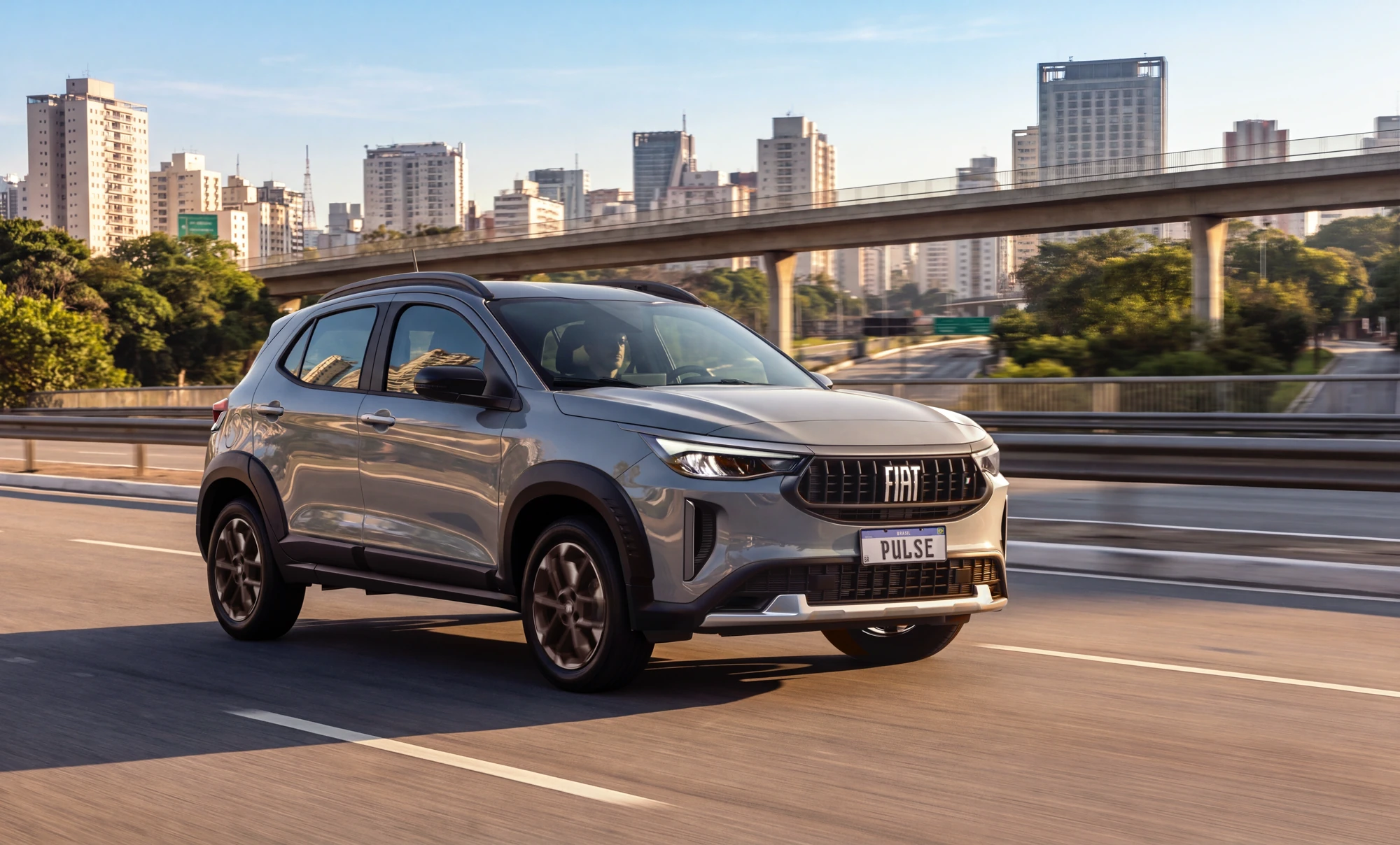 Fiat Pulse T200 Flex MHEV 12 V na cidade Fiat Pulse T200 Flex MHEV 12 V cinza, com teto preto, rodando em via urbana com prédios ao fundo e com faróis em LED acesos.